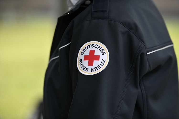 Symbolfoto: Eine dunkelblaue, modische Dienstjacke einer Führungskraft mit dem Rundlogo des DRK im Fokus